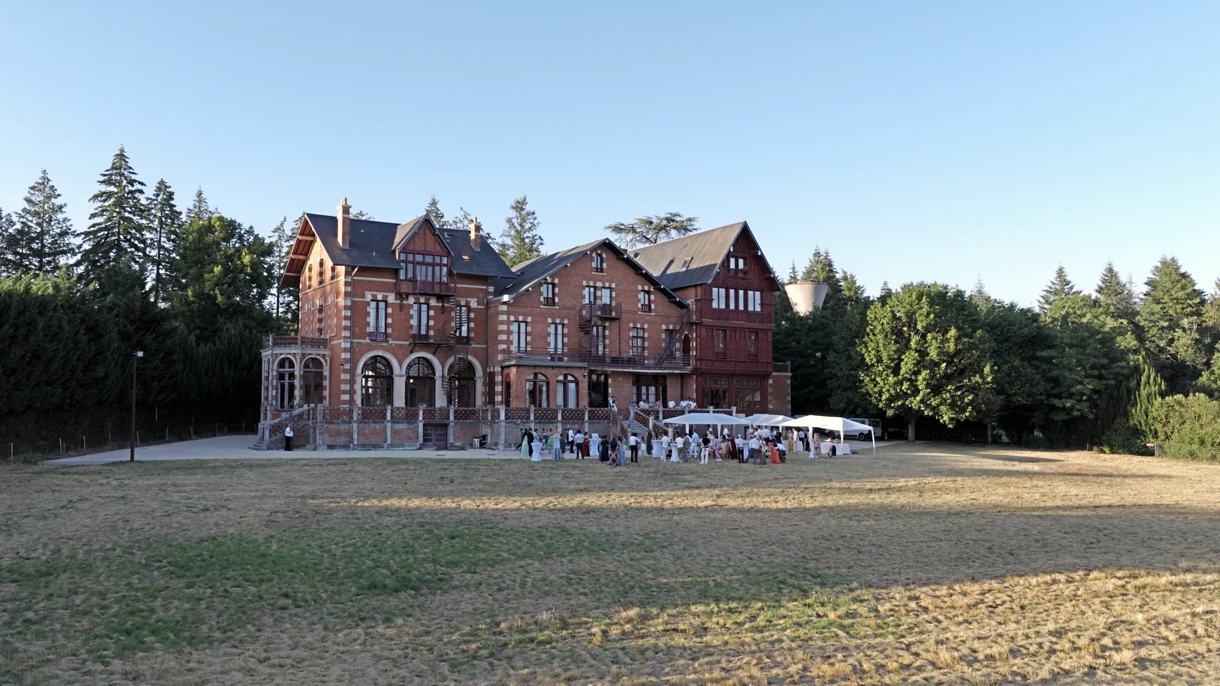 La façade du château de La Luzière depuis le parc, un soir d'été